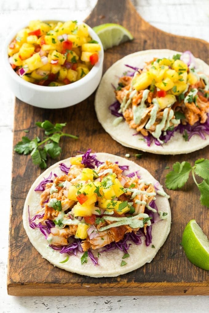 Mini corn tortillas topped with purple cabbage and pulled chicken.