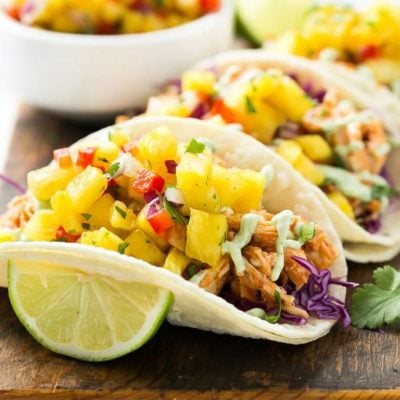 This recipe for pulled chicken tacos with pineapple salsa is flavorful shredded chicken combined topped with sweet and tangy salsa and creamy cilantro sauce, all stuffed inside warm corn tortillas.