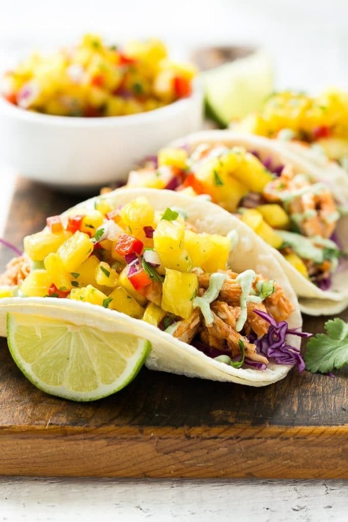 A platter of pulled chicken tacos topped with pineapple salsa.