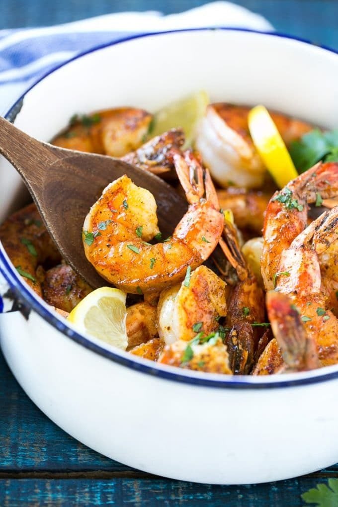 A wooden spoon serving up a portion of New Orleans BBQ shrimp.