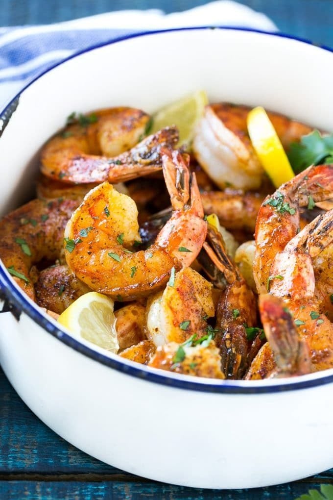 A pot of New Orleans BBQ shrimp garnished with lemon wedges and parsley.