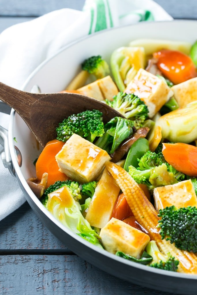 Tofu stir fry in a skillet with a serving spoon.