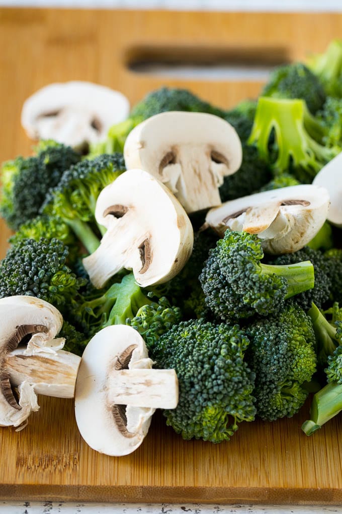 Broccoli florets and sliced mushrooms on a cutting board.