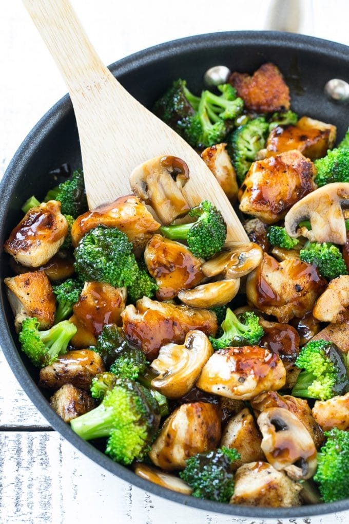 Chicken and broccoli stir fry with mushrooms in a skillet with a spatula.