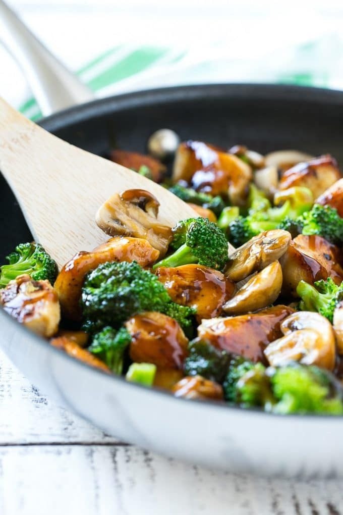 A pan of chicken and broccoli stir fry with a spatula in it.