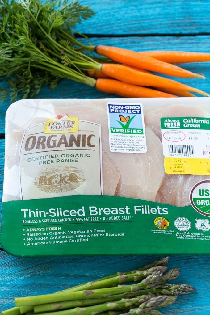 A package of organic chicken breasts and a bunch of carrots.