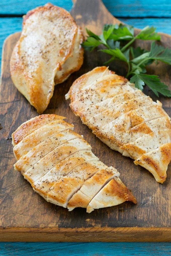 Sliced cooked chicken breasts on a cutting board.