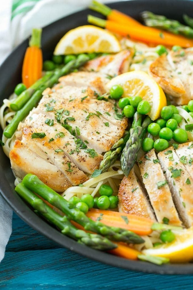 A skillet of chicken primavera pasta with peas, carrots and asparagus.