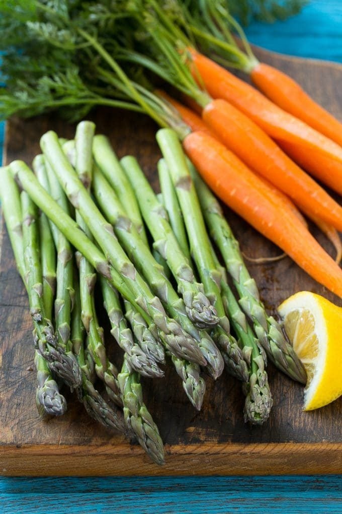 Fresh asparagus and carrots on a cutting board.