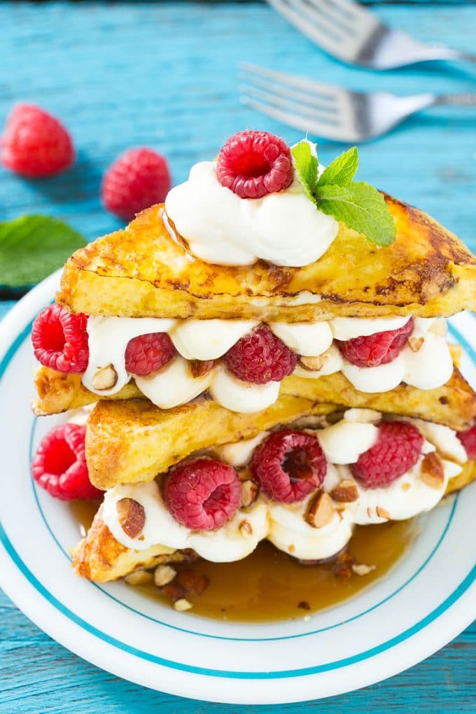 Stuffed French Toast | Cream Cheese Stuffed French Toast | French Toast Recipe #frenchtoast #raspberry #creamcheese #breakfast #brunch #dinneratthezoo A plate of cooked brioche filled with cream cheese, berries and almonds.