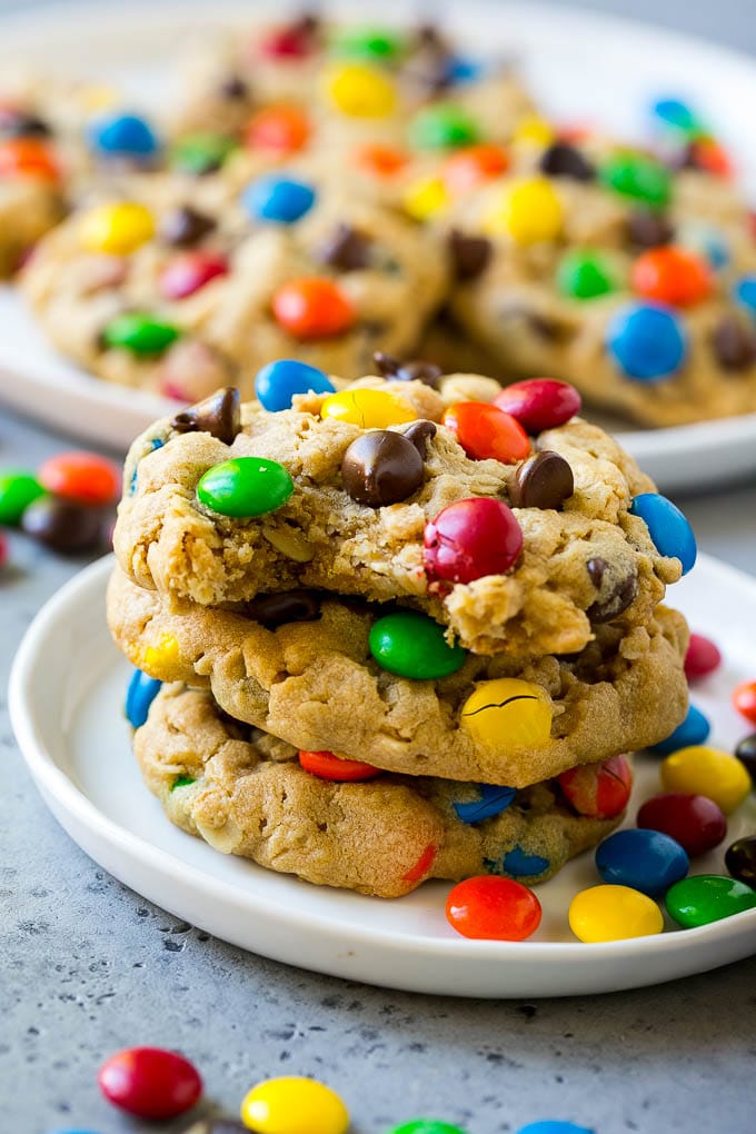 A stack of monster cookies with a bite taken out of one.