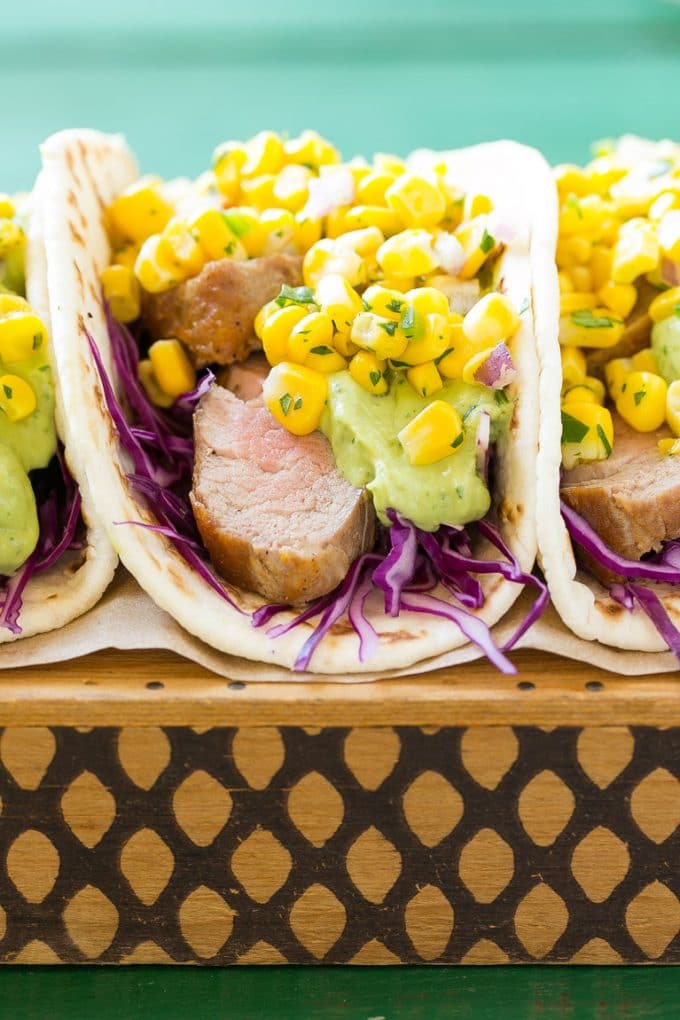 This recipe for pork tenderloin tacos is thinly sliced seasoned pork, layered with cabbage, corn salsa and creamy avocado sauce, all tucked inside warm flour tortillas. A unique take on taco night!