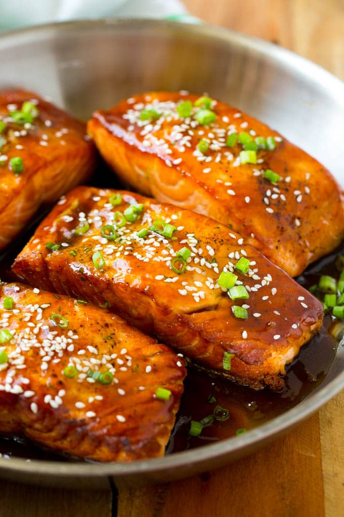 A pan full of teriyaki salmon fillets topped with sesame seeds.