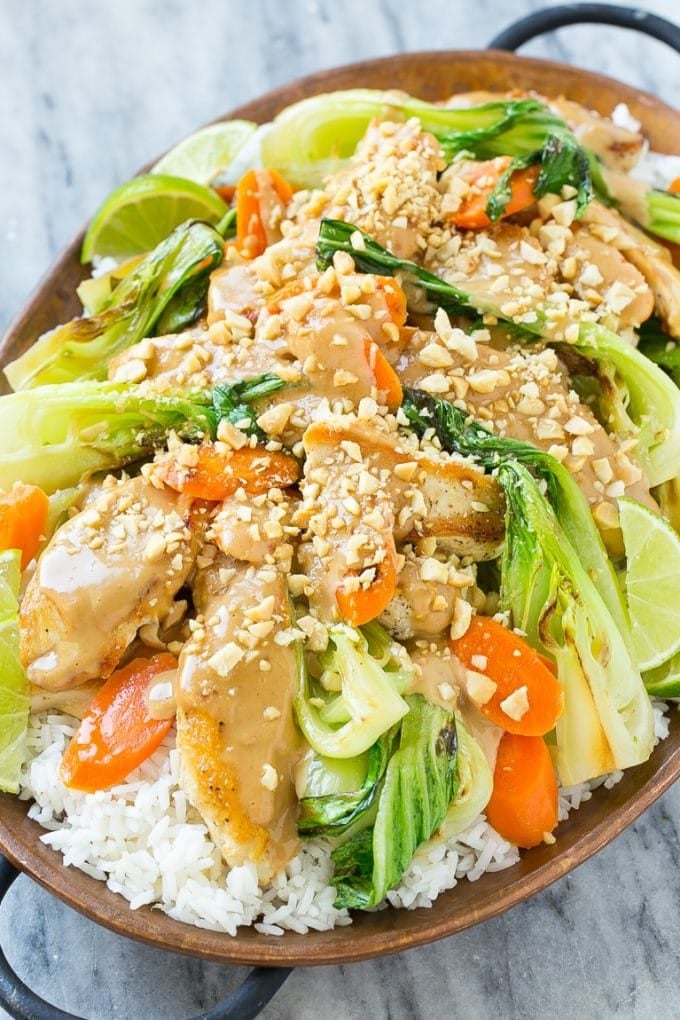 Thai peanut chicken in a skillet with carrots, bok choy and chopped peanuts.