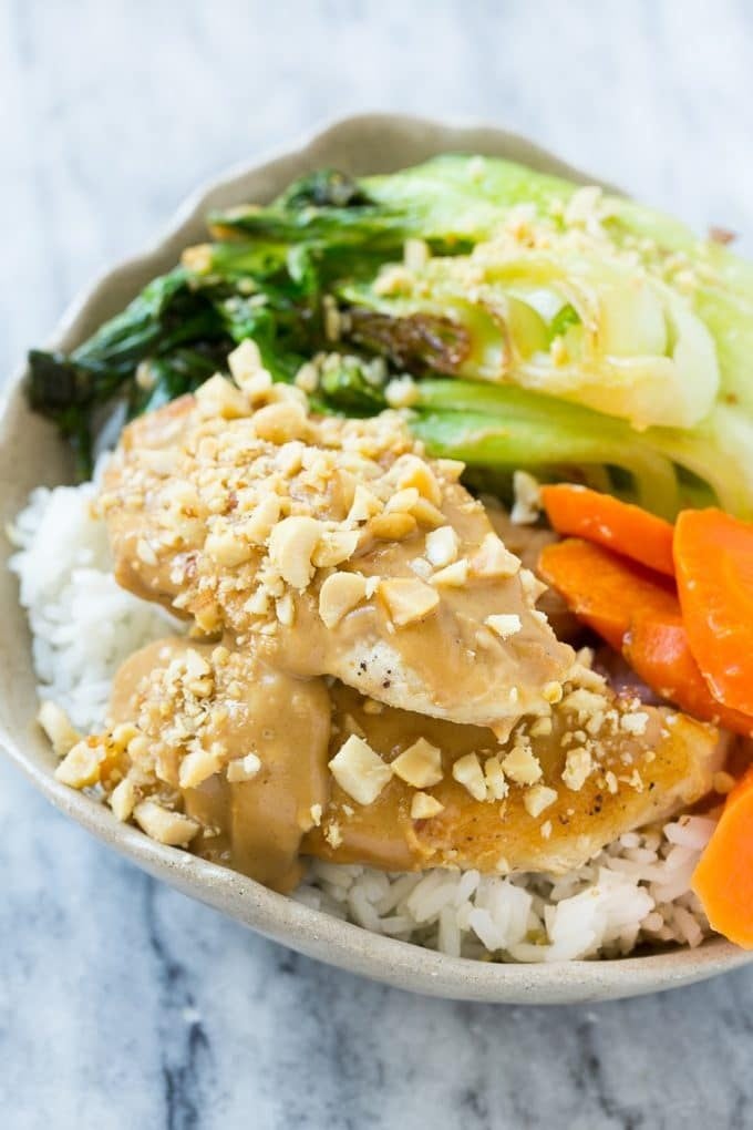 A bowl of Thai peanut chicken and vegetables served over steamed rice.