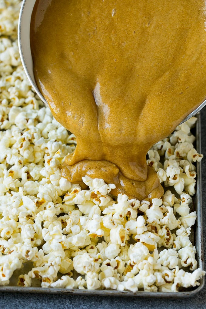 Caramel being poured over a pan of popcorn.