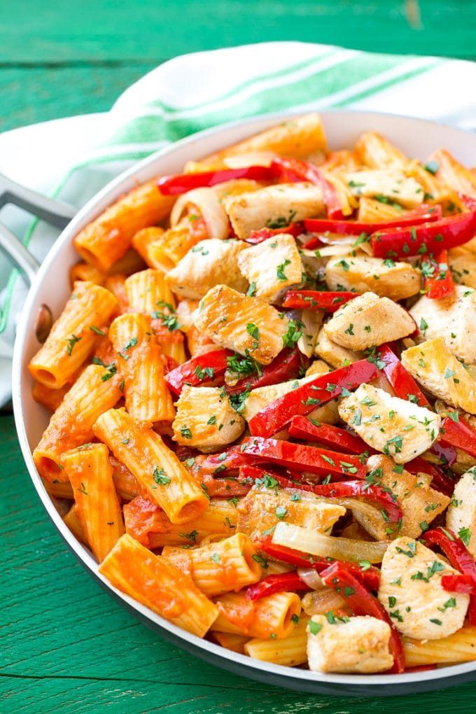 A pan full of chicken riggies pasta topped with red bell peppers and parsley.