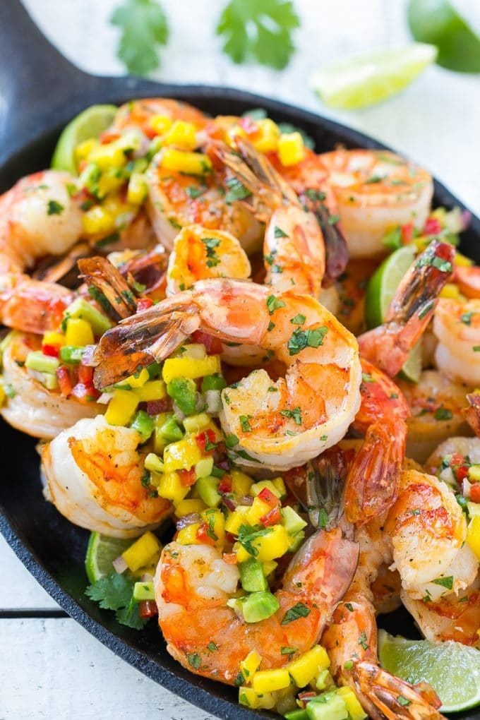 Cilantro lime shrimp on a skillet, topped with mango and avocado salsa.