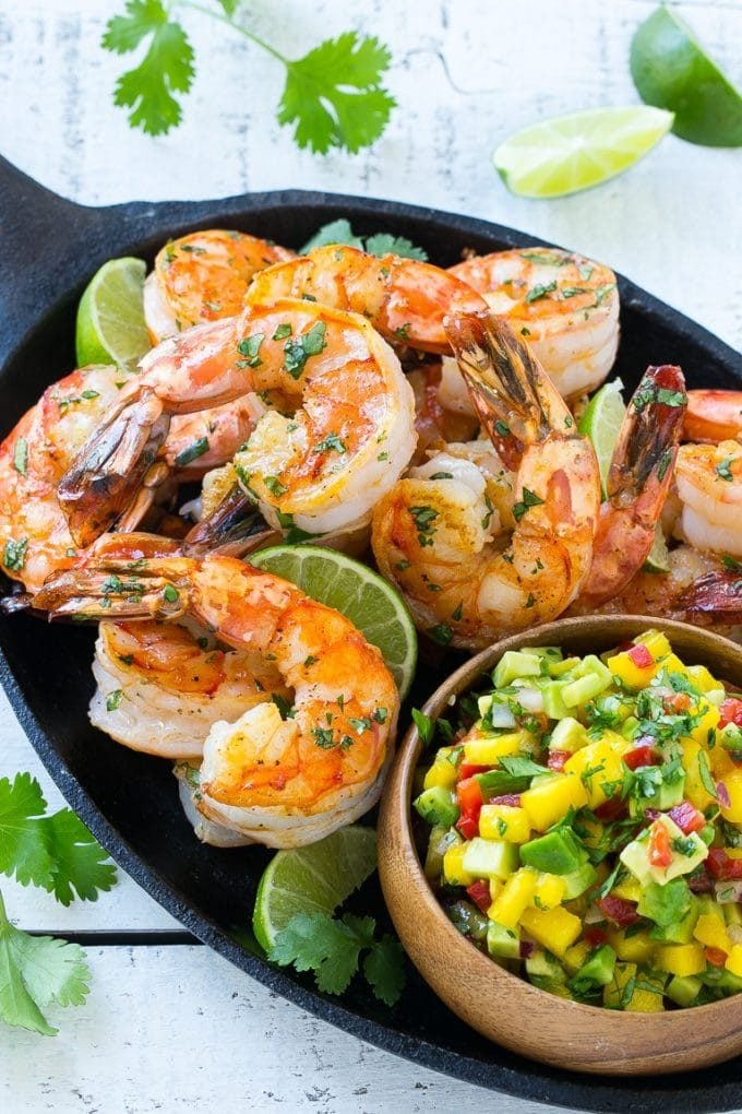 A pan of seared cilantro lime shrimp with a fruit salsa topping.