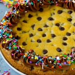 A cookie cake topped with chocolate frosting and sprinkles.