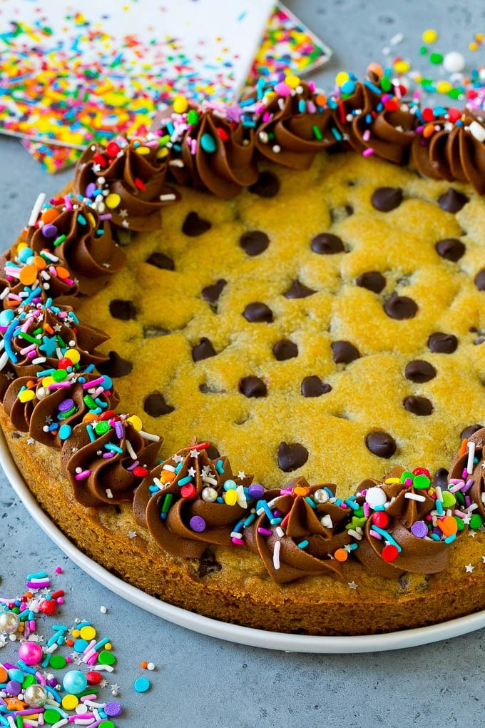 A cookie cake topped with chocolate frosting and sprinkles.