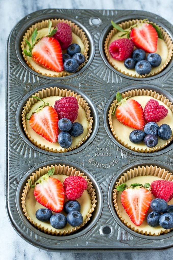 Greek yogurt cheesecakes in muffin cups garnished with fruit.
