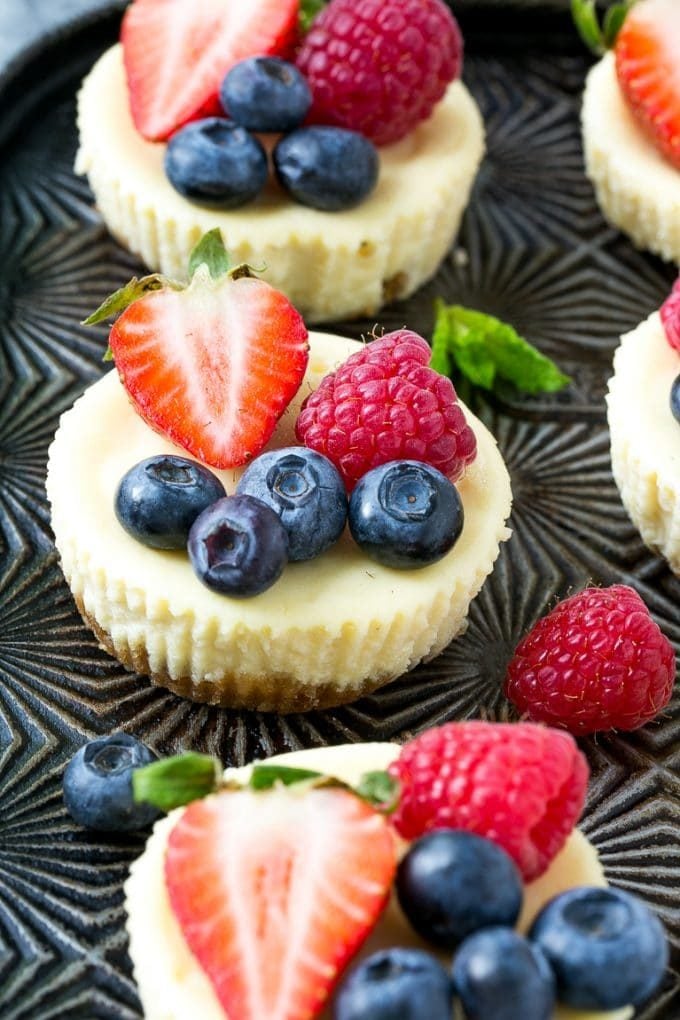 Mini Greek yogurt cheesecakes topped with fresh berries and garnished with mint.