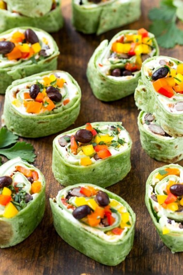 This recipe for Mexican tortilla pinwheels is two types of cheese, black beans and colorful veggies all rolled up inside tortillas and cut into rounds. The perfect make-ahead snack or appetizer!