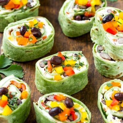 This recipe for Mexican tortilla pinwheels is two types of cheese, black beans and colorful veggies all rolled up inside tortillas and cut into rounds. The perfect make-ahead snack or appetizer!