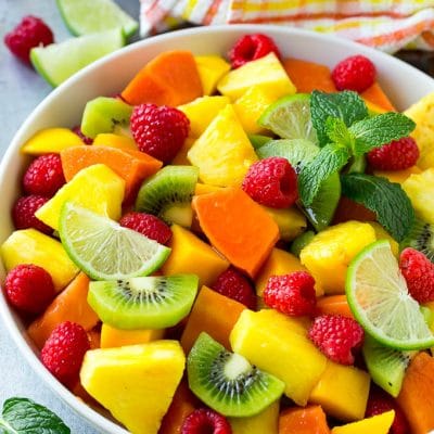 A bowl of tropical fruit salad with mango, raspberries, papaya, kiwi and pineapple tossed in honey lime dressing.