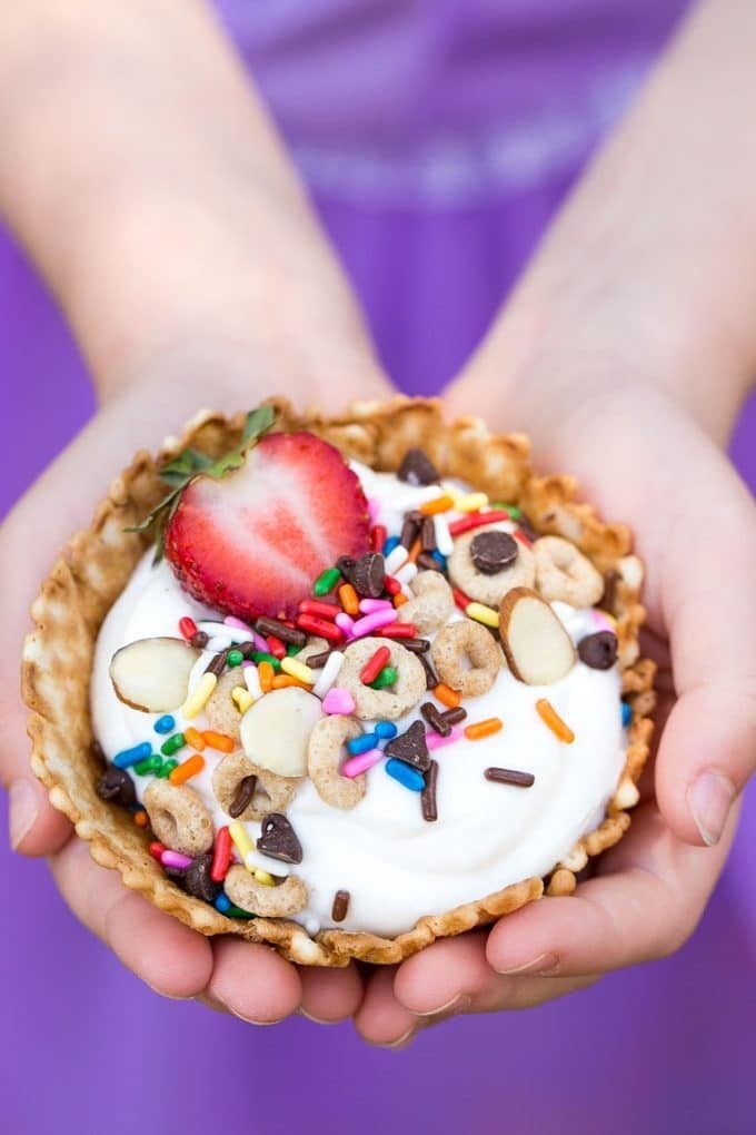 Children's hands holding a breakfast sundae.