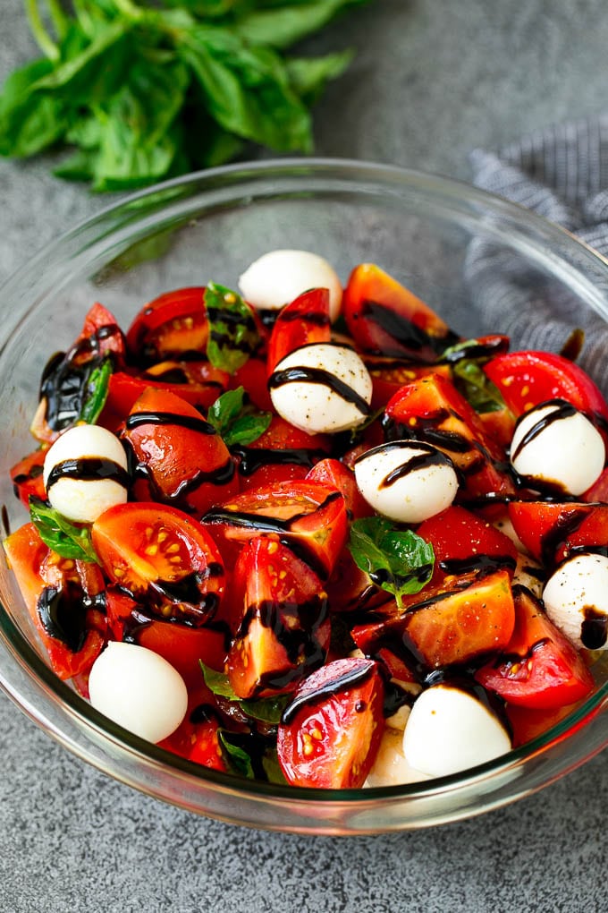 Caprese salad with tomatoes, fresh mozzarella, basil leaves and balsamic glaze.
