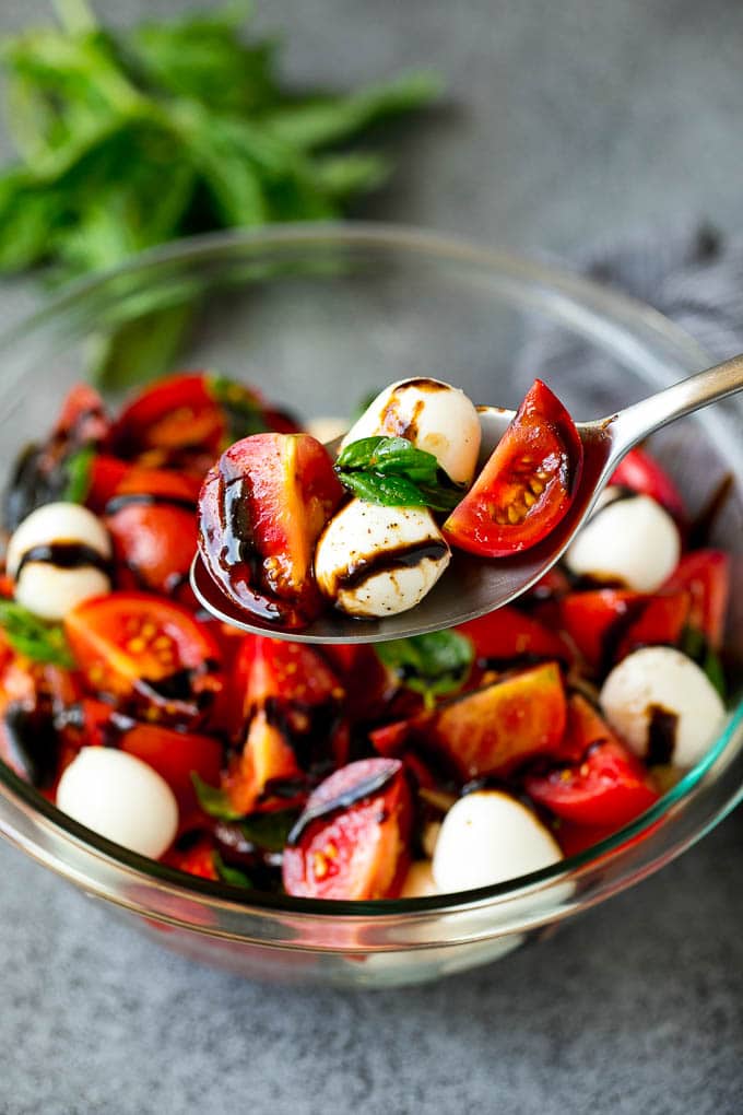 A serving spoon of caprese salad with tomato, mozzarella and basil.