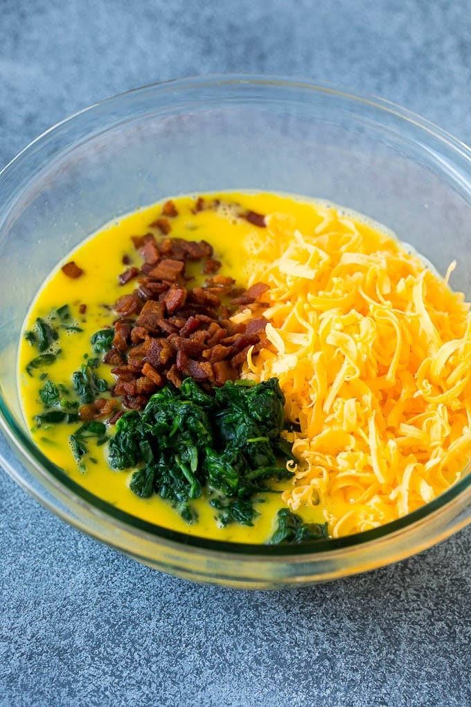 Bacon, beaten eggs, cheese and spinach in a mixing bowl.