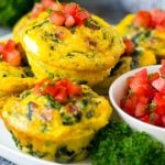 Egg muffins on a serving plate topped with diced tomatoes.
