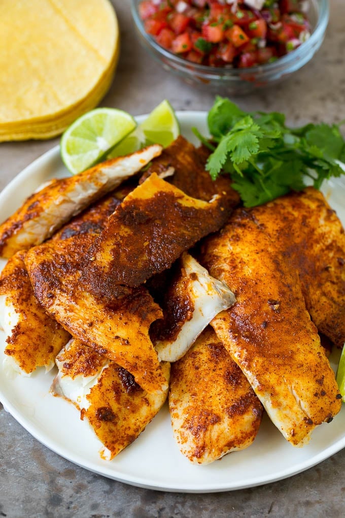 A plate of taco seasoned fish fillets with a lime and cilantro garnish.