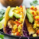 This recipe for tilapia fish tacos is seasoned fish layered with cabbage, avocado and a tropical salsa, all tucked inside warm corn tortillas. It's a meal that's fast, fresh, healthy and ready in 20 minutes!