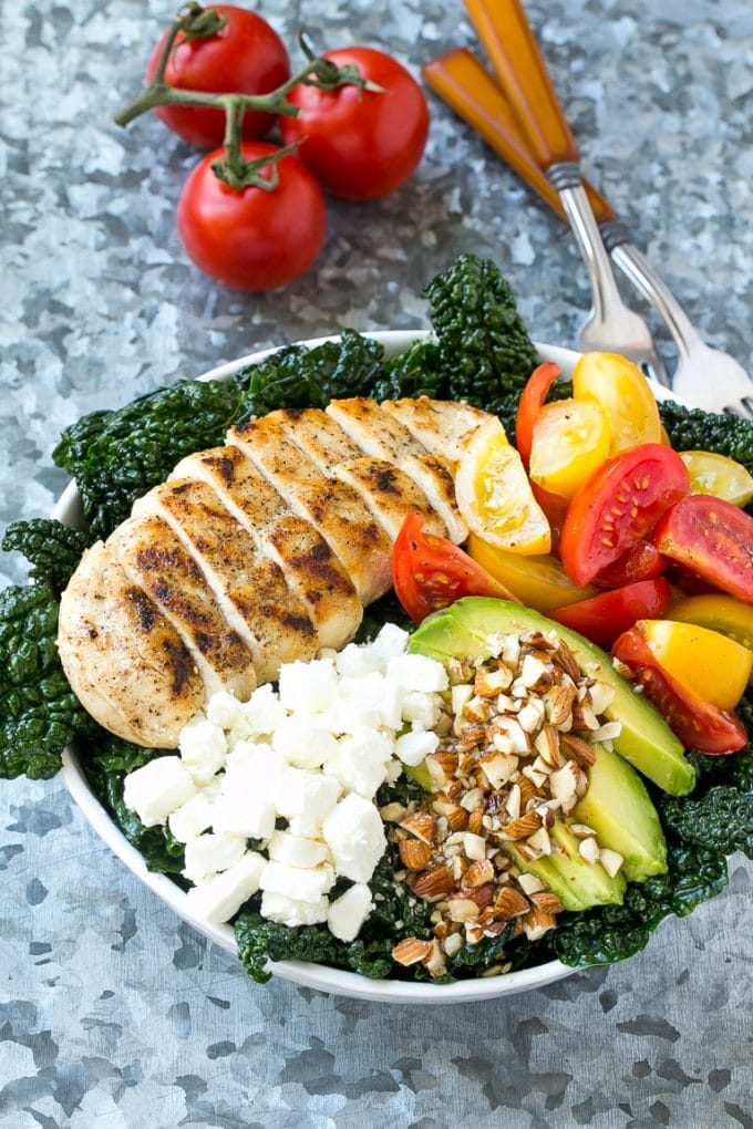 Tuscan kale salad topped with grilled chicken, crumbled feta cheese and sliced avocado.