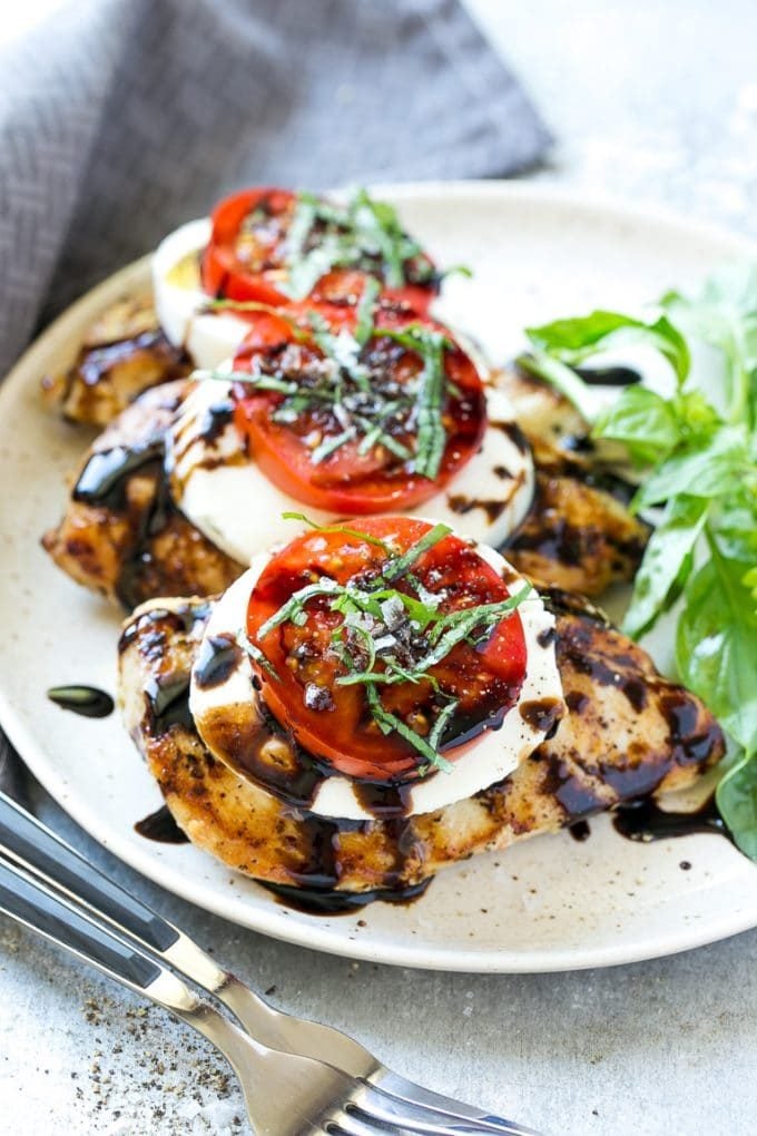 Grilled chicken breasts topped with sliced cheese, tomatoes and basil.