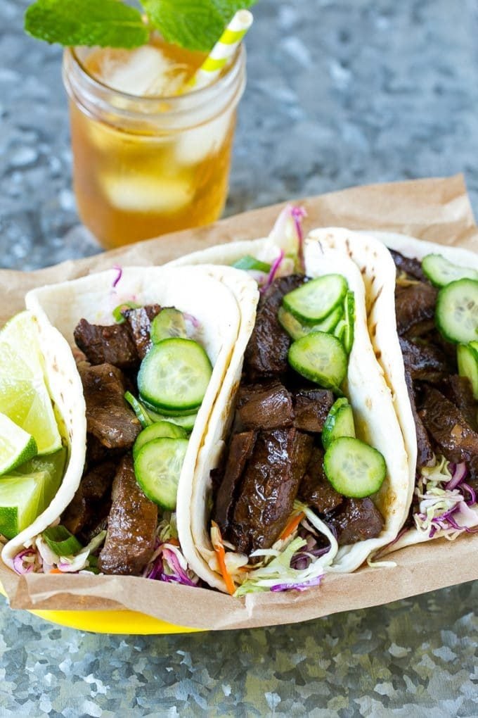 A basket of Korean beef tacos served with iced tea.