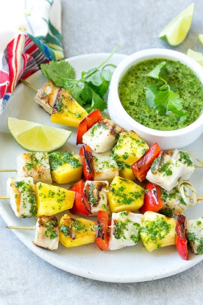 Mojo fish kabobs with pineapple and peppers on a serving plate.