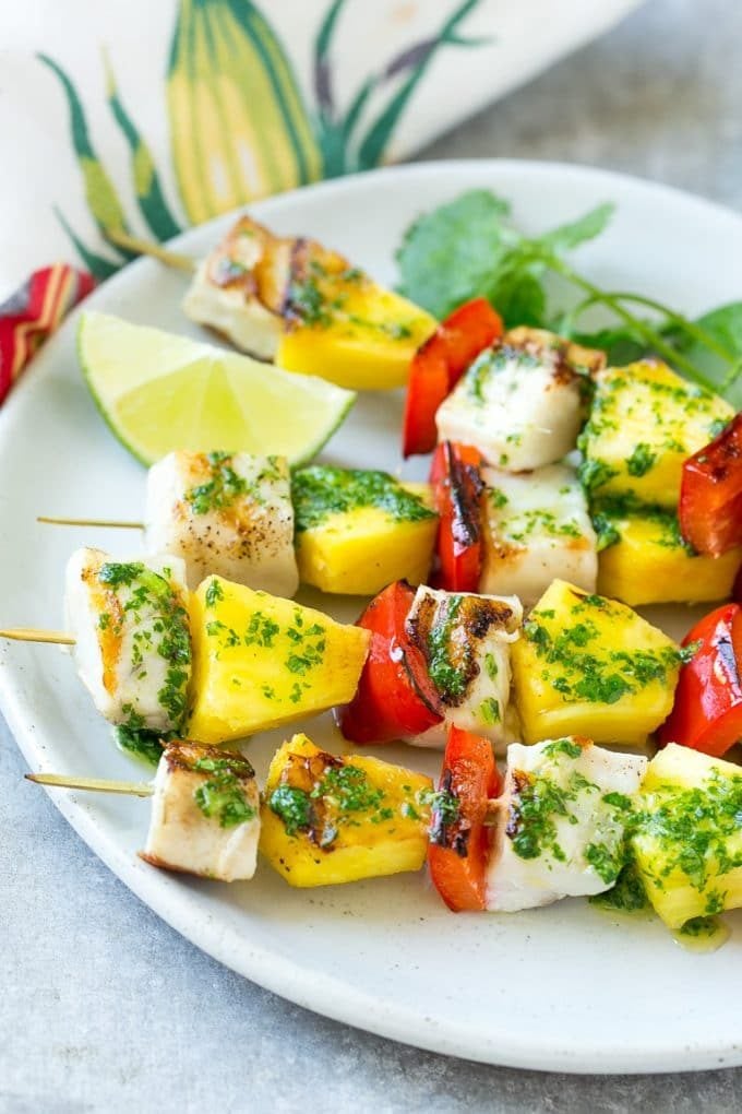 Mojo fish kabobs with lime wedges and cilantro for garnish.