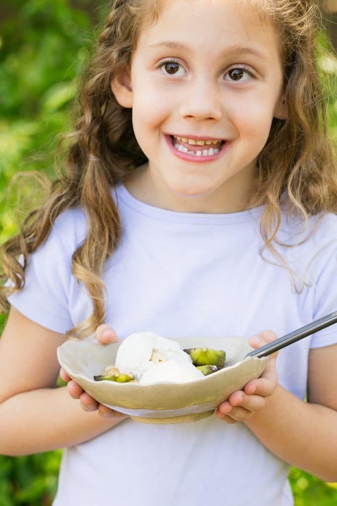 A girl holding a bowl of roasted figs with ice cream.