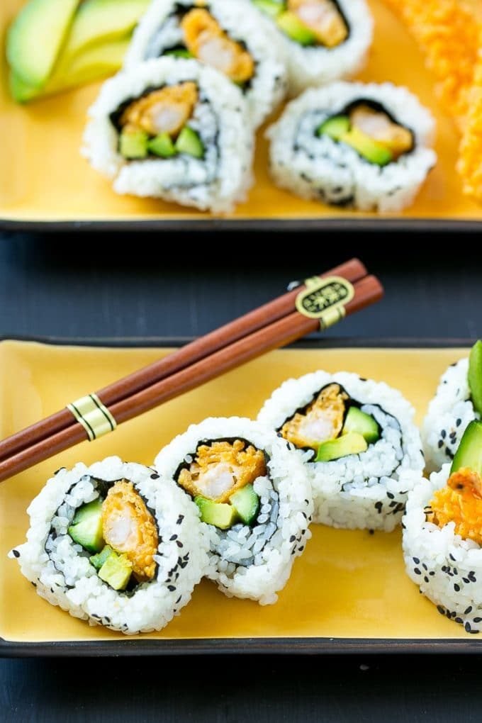 Shrimp tempura sushi wrapped in seaweed and rice and garnished with sesame seeds.