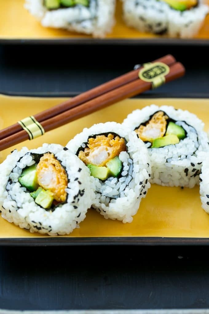 Sliced shrimp tempura roll sushi on a serving plate.