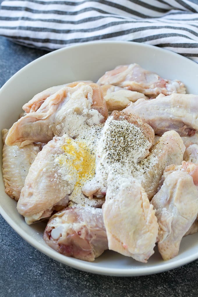 Chicken wings in a bowl with baking powder and seasonings.