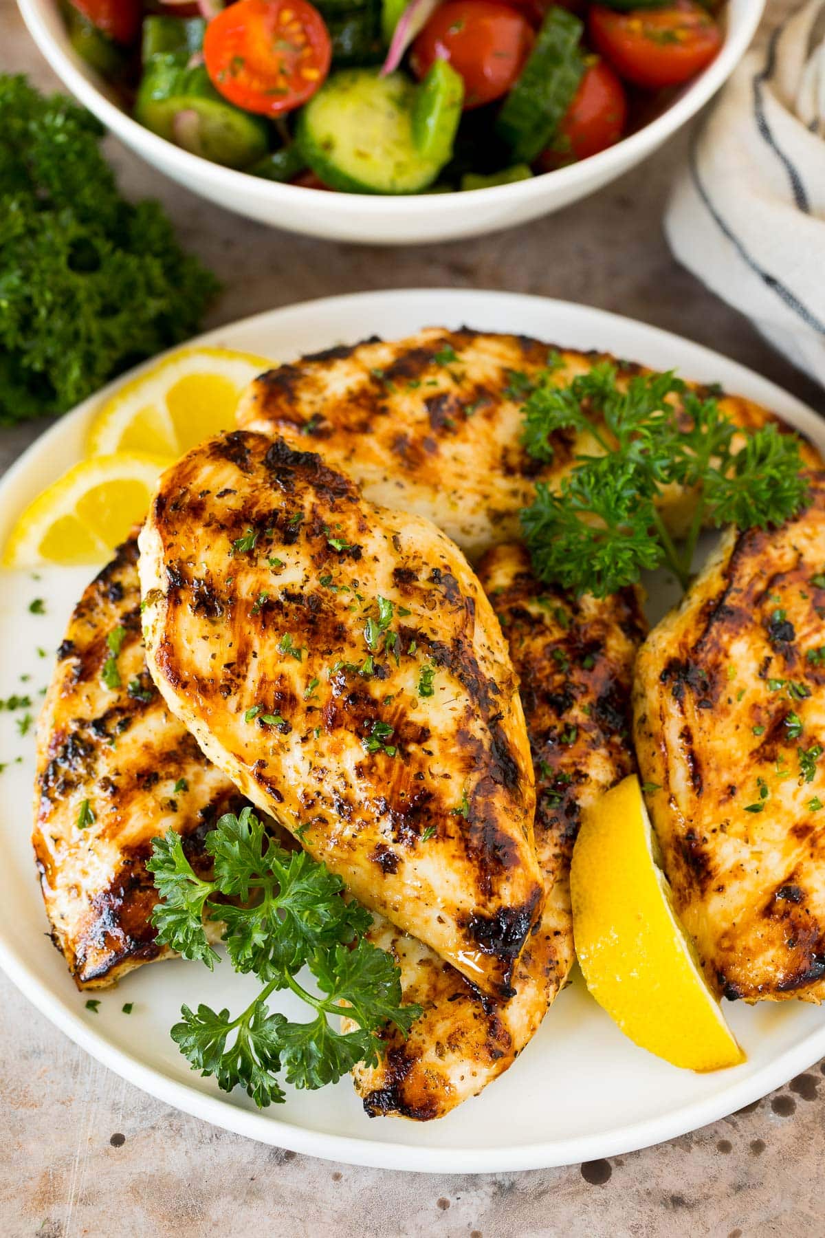 Greek lemon chicken on a plate with lemon and herbs.