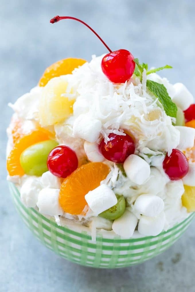 A bowl of ambrosia salad with a variety of colorful fruit with marshmallows and coconut, tossed in a light and creamy dressing.