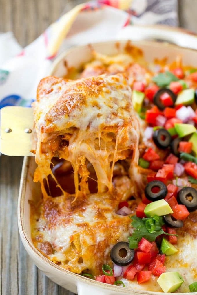 A spatula serving up a portion of cheesy chicken enchilada casserole.