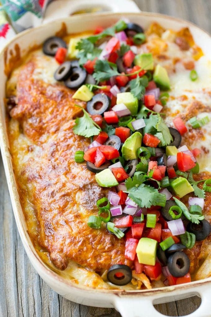 Chicken enchilada casserole topped with avocado, tomatoes and olives.